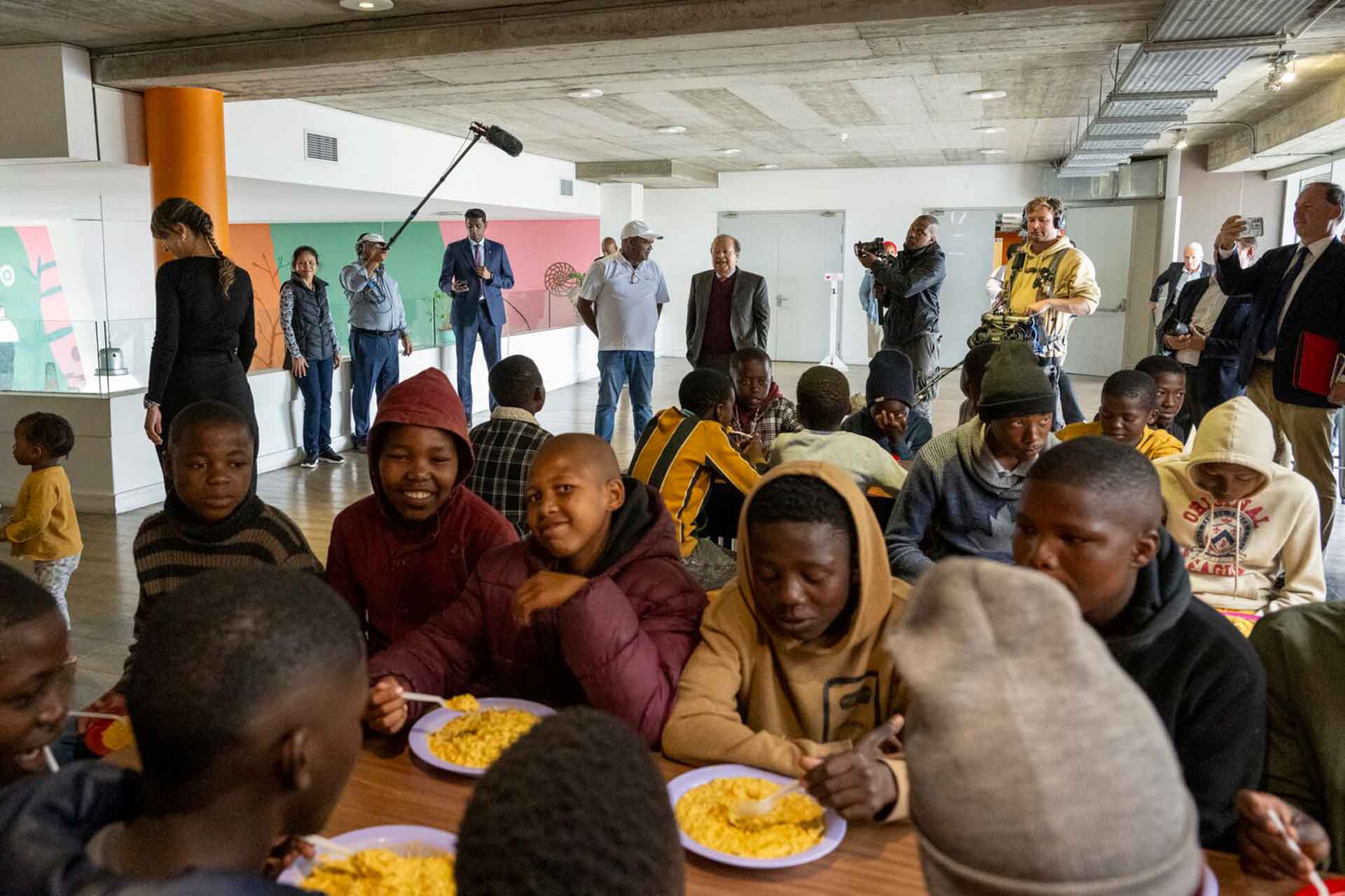  Prem Rawat speaks with the head chef at the Food For People facility in Cape Town (2024), as children enjoy their second meal of the day.